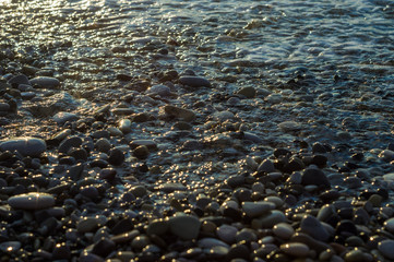 pebble stones on the sea beach, the rolling waves of the sea with foam