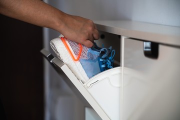 Close up of a hand taking a pair of sport shoes from a shoe rack before going out to take a run due to the permission of the spanish Government to go out one hour a day to practice sport