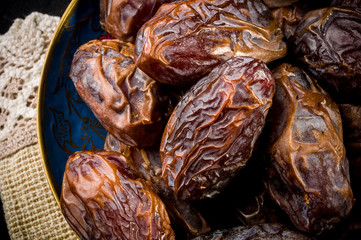 Big luxury dried date fruit in bowls on a linen napkin, kurma ramadan kareem concept, close up.