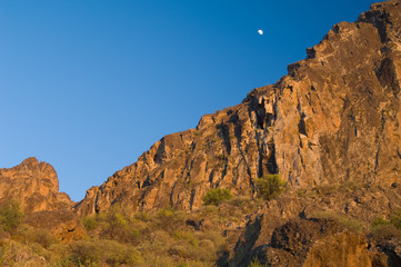 Moon over a cliff at sunset in the Roque Nublo Natural Monument. The Nublo Rural Park. Tejeda. Gran Canaria. Canary Islands. Spain.