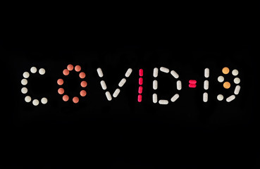 Word COVID-19 made from different medical pills on black background. Stop coronavirus. Many pills and tablets with space for text. Health care. Top view. Copy space. New image. Pharmaceutical pills