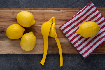 Lemons on a cutting board with a lemon squeezer and a kitchen towel on the counter