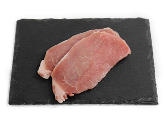 raw meat isolated on black plate. Two pieces of pork on black plate
