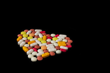 Many different pills and tablets folded in shape of heart on black background. Many pills and tablets with space for text. Health care. Top view. Copy space. New image. Closeup. Close-up. Soft focus