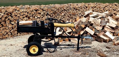 Wood splitter with heap and piled wood behind