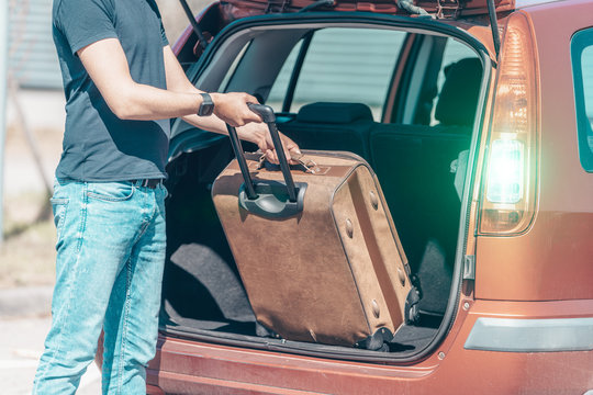 The Young Man Pulls Luggage From The Car Trunk