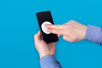Man, hands and wipe the mobile phone screen with a cotton swab with antiseptic for disinfection. Ncov - 19 coronavirus prevention. The concept of protection and security