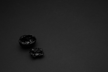 Black walnut shell on a matte black background. Copy space. Dark mode