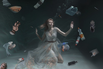 Ecological pollution of the planet and water. Garbage under water. Girl under water in a dress....