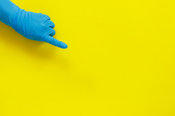 Hand in medical glove pointing finger on yellow paper background