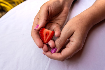 one red strawberry in the palm of a woman's hand