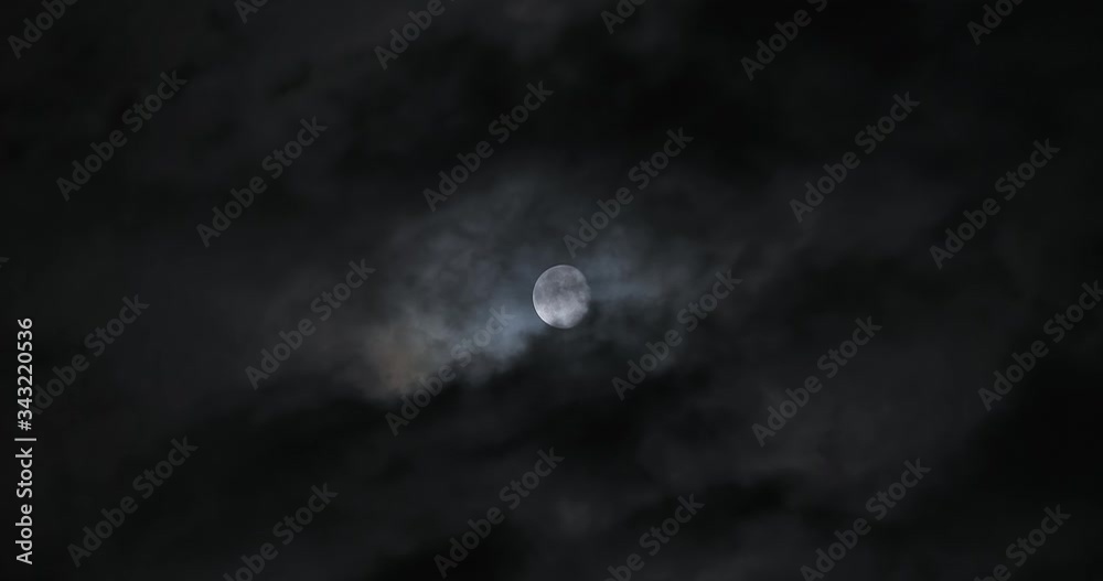 Wall mural moon shot behind dark clouds moving at night in real time