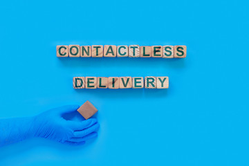 Cardboard boxes with groceries or other purchases on a blue background. Hand in a medical glove with box. The inscription on wooden cubes 