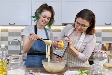 Mother and teenager daughter cook together at home in kitchen