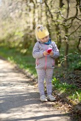 Little girl in the park holding a smartphone in his hand, child's portrait.