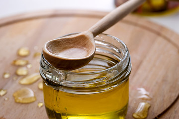 Honey with a wooden honey ladle drips on a wooden table