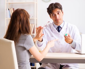 Obraz premium Young woman visiting male doctor ophthalmologist in hospital