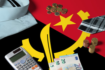 Angola flag on minimal money concept table. Coins and financial objects on flag surface. National economy theme.