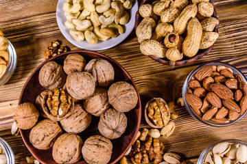 Various nuts (almond, cashew, hazelnut, pistachio, walnut) in bowls on a wooden table. Vegetarian meal. Healthy eating concept. Top view