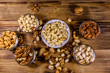 Various nuts (almond, cashew, hazelnut, pistachio, walnut) in bowls on a wooden table. Vegetarian meal. Healthy eating concept. Top view