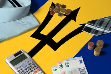 Barbados flag on minimal money concept table. Coins and financial objects on flag surface. National...