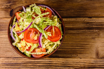 Vegan salad with savoy cabbage, tomatoes and onion in a ceramic bowl. Top view