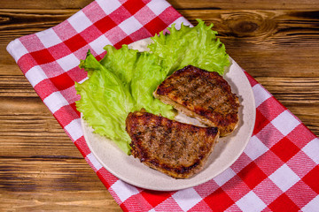 Plate with roasted steaks and rosemary twigs on a wooden table