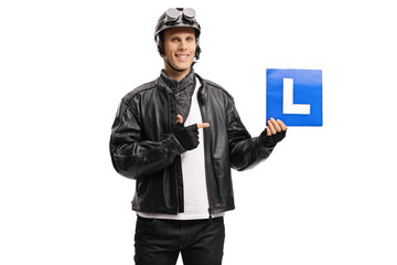 Young man biker holding a drivers learning plate and pointing
