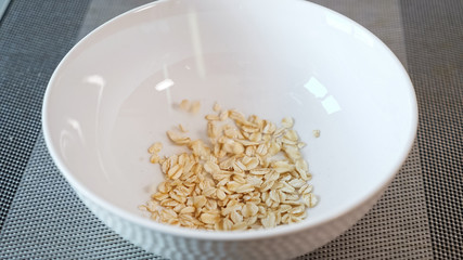 delicious yellow porridge cereals fall into white ceramic bowl on grey table in morning extreme close view
