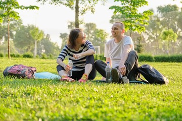 Fototapeta premium Middle-aged couple sitting on yoga mat, man and woman talking relaxing drinking water