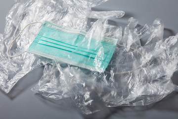 Disposable plastic protective gloves and medical protective mask on gray background, close-up shot,...