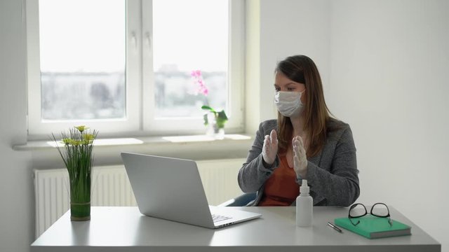 Young woman working at laptop computer in office mask during epidemic covid-19