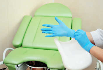 doctor gynecologist putting on rubber gloves prepares for examination against the background of a...