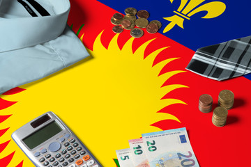 Guadeloupe flag on minimal money concept table. Coins and financial objects on flag surface. National economy theme.