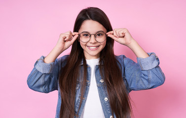 Fashionable stylish young Caucasian girl in jeans and glasses.