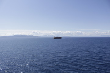 A marine ship goes into the distance against the background of islands and a blue sky.
