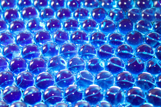 Water blue gel balls with boke. Polymer gel. Silica gel. Balls of blue hydrogel. Crystal liquid ball with reflection. Texture background. Macro