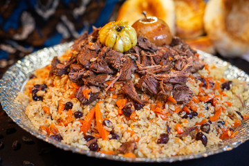 Pilaf and ingredients on plate with oriental ornament on a black background. Central-Asian cuisine - Plov Top view