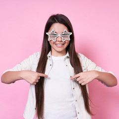 Cute funny beautiful emotional young lady in stylish glasses,in a white T-shirt on a pink...