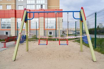 Swing for children and Tape barrier in a closed playground during the period of quarantine and pandemic covid-19, Coronavirus.