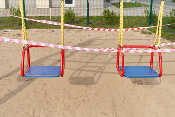 Swing for children and Tape barrier in a closed playground during the period of quarantine and pandemic covid-19, Coronavirus.