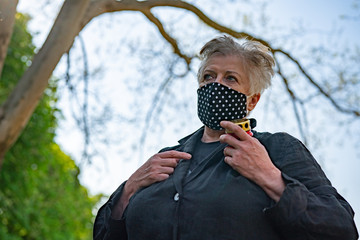 Senior woman in black dotted mask in a cemetery