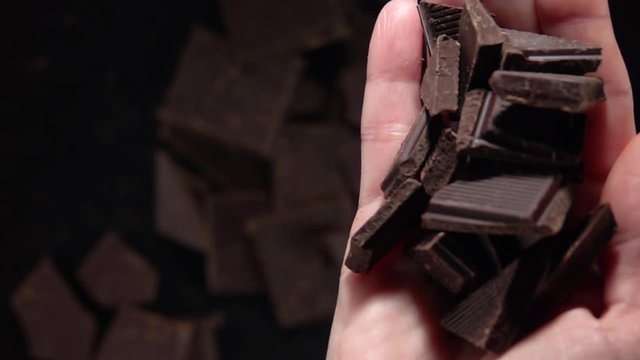 Girl pours pieces of chocolate from her hand. Slow Motion 500fps