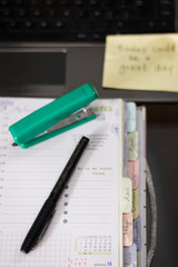 agenda on desk with black pen and green button working from home