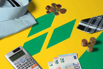 Saint Vincent And The Grenadines flag on minimal money concept table. Coins and financial objects on flag surface. National economy theme.