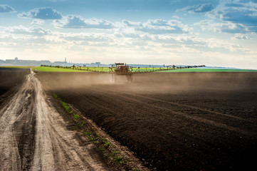 self-propelled sprayer with long arms fertilizes fields at springtime