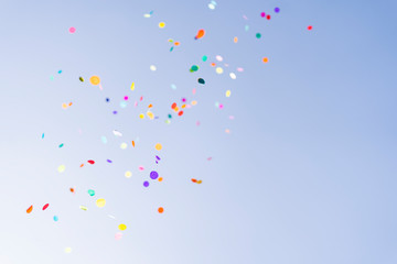 Colorful confetti thrown against blue sky celebration sunshine party