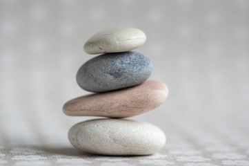 Stone cairn on striped grey white background, four stones tower, simple poise stones, simplicity harmony and balance,