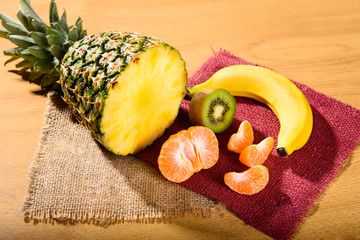 set of fresh dietary tropical exotic fruits on a wooden background pineapple banana kiwi mandarin