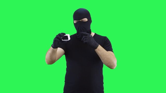 A man in a balaclava takes pictures of himself on an action camera holding it in his hands,green screen background